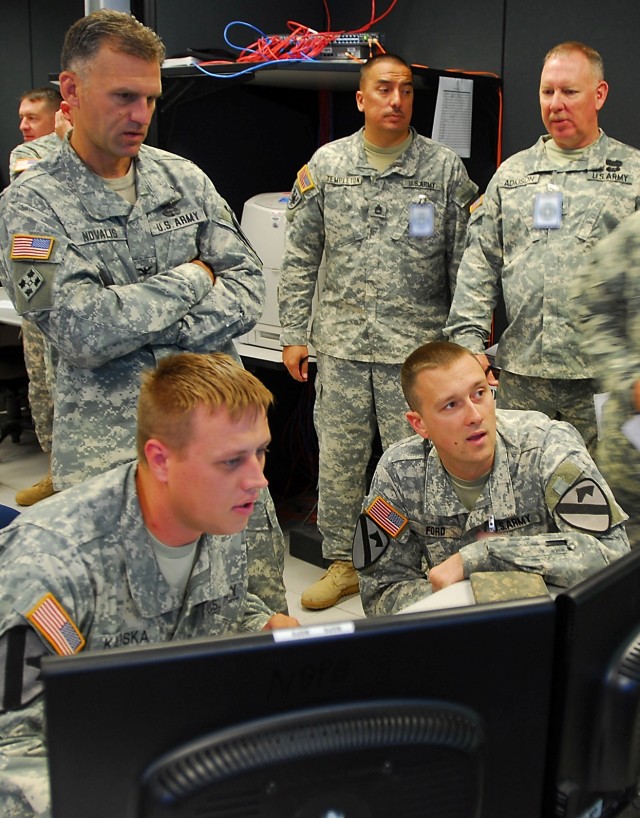 FORT RUCKER, Ala. - Col. John Novalis II (standing left), brigade commander of the 1st Air Cavalry Brigade, 1st Cavalry Division, looks on as Soldiers work in the brigade tactical operations center during their week long aviation training exercise...