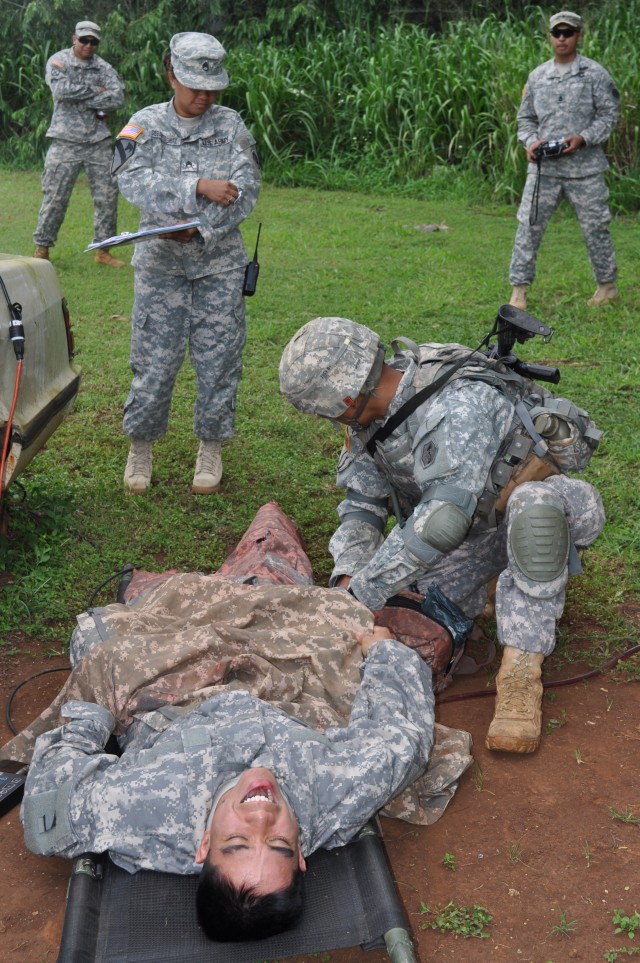 SCHOFIELD BARRACKS, Hawaii -- Sgt. Marc-Anthony Ho, a sniper with the 100th Battalion, 442nd Infantry Regiment, treats a casualty suffering from a simulated dual-leg amputation as part of a medical exercise during this year's 9th Mission Support...