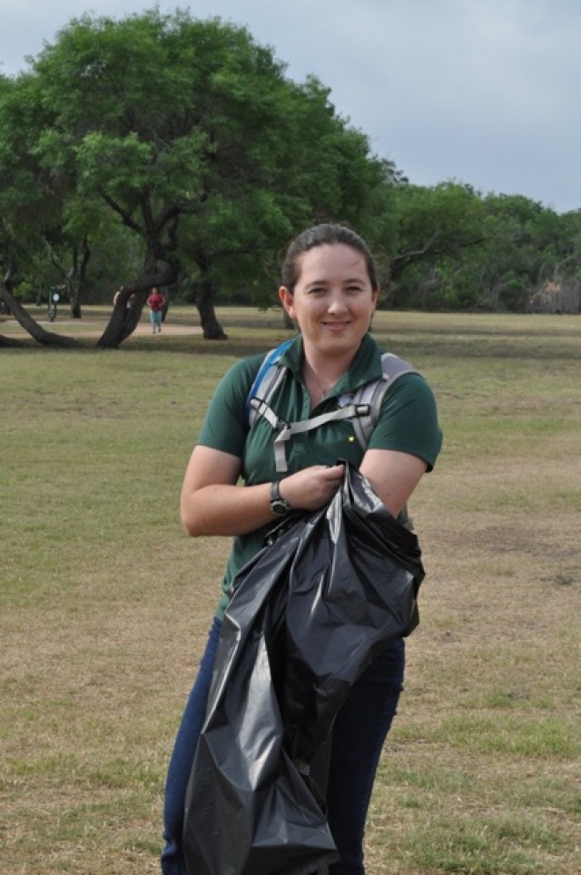 A volunteer picks up trash at John James Park for Earth Day.