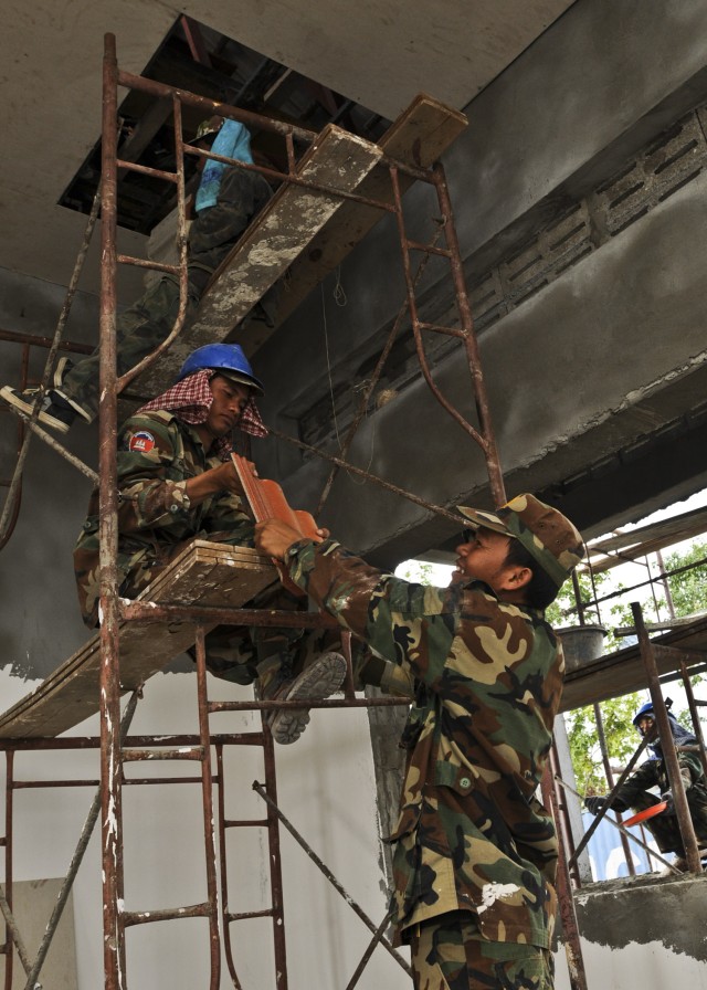 Cambodian engineers pass ceiling tiles