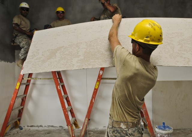 Soldiers place gypsum board on walls of school