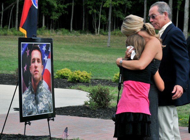Ginny Gaudet, wife of fallen Chief Warrant Officer 2 Bradley J. Gaudet (pictured), pilot in command with 1st Battalion, 10th Aviation Regiment, 10th Combat Aviation Brigade, holds their 10-year-old daughter, Tealie, while her father, Ed Van...
