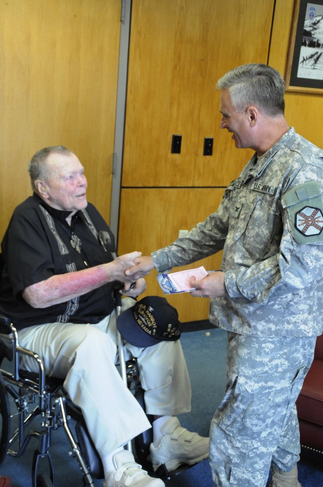 Col. Noel T. Nicolle, Fort Drum garrison commander, presents a coin to retired Navy Capt. Robert J. Norman on Monday during a visit to Fort Drum. Norman's son, retired Army Col. Kurt D. Norman, who resides in Sackets Harbor, brought his father on pos...