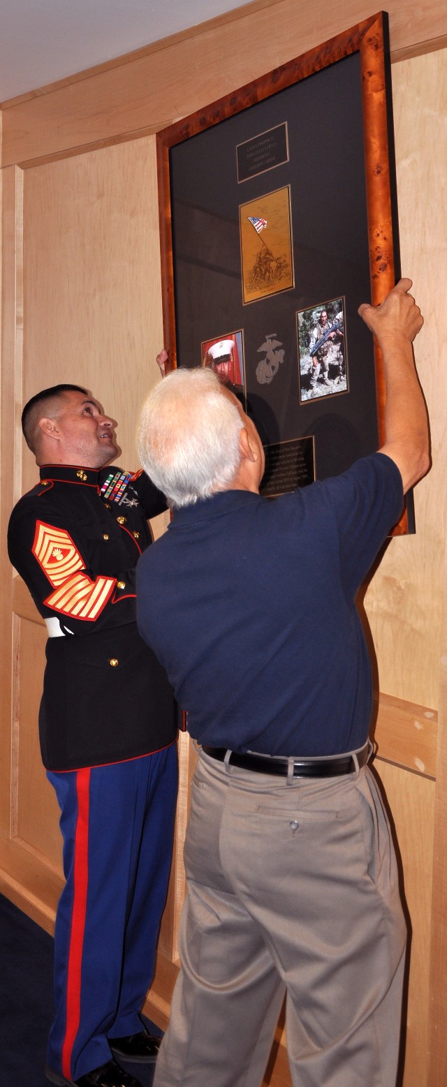 Garza and Felix Farias hang a plaque