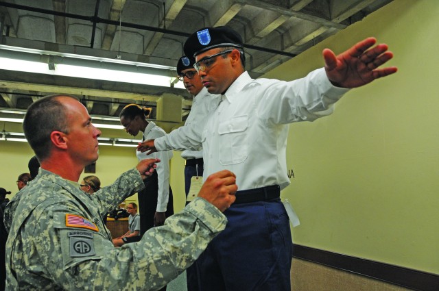 Drill sergeant inspects basic trainees uniform