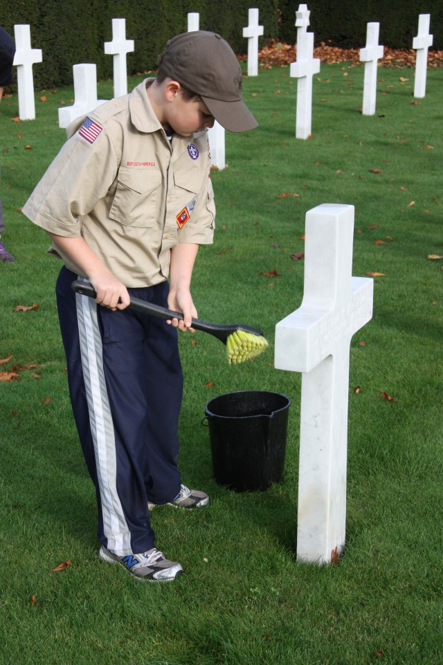 Benjamin Mouritsen, 11, from Heidelberg's Boy Scout Troop 59, scrubs the headstone of an American who lost his life near Flanders Field, Belgium, during World War I. Thirteen Scouts and two leaders sc