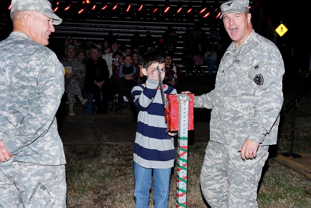 Child assists with the lighting of a Christmas tree at Eustis (DCG-IMT looks on)