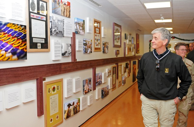 Secretary of the Army admires the remembrance wall at Kandahar Airfield's Role 3