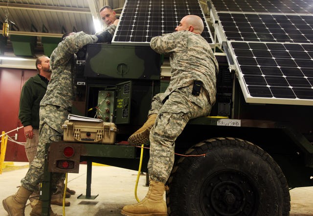 Soldiers of the 173rd Airborne Brigade Combat Team install a solar panel to an energy-efficient generator