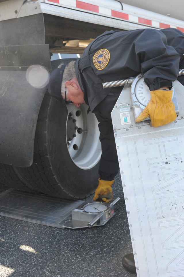 John Griffin, Department of Motor Vehicles, Size and Weight Compliance agent, sets portable scales in place for a motor carrier weight inspection.