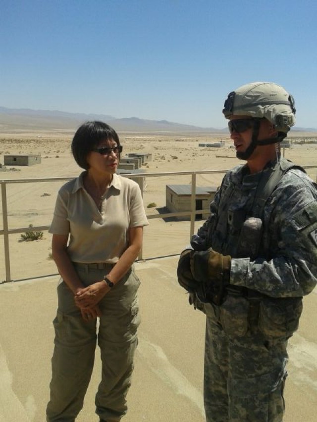 Ms. Shyu on roof of building talking to Soldier w desert background