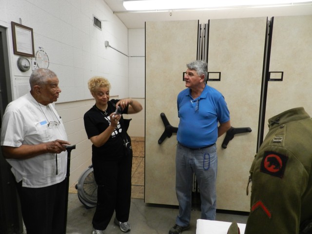 Army Intelligence Historic Holding curator Paul Pipik (right) gives retired Capt. Joseph Hairston and daughter, Naomi Henderson (center) a sneak peek at a uniform with a 92nd Infantry Division patch t