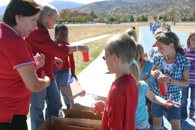 Fort Huachuca Alcohol and Substance Abuse Program Training Specialist Kathy Thomson and Prevention Program Volunteer Rosa Peralta hand out red water bottles to General Myer Elementary School third gra