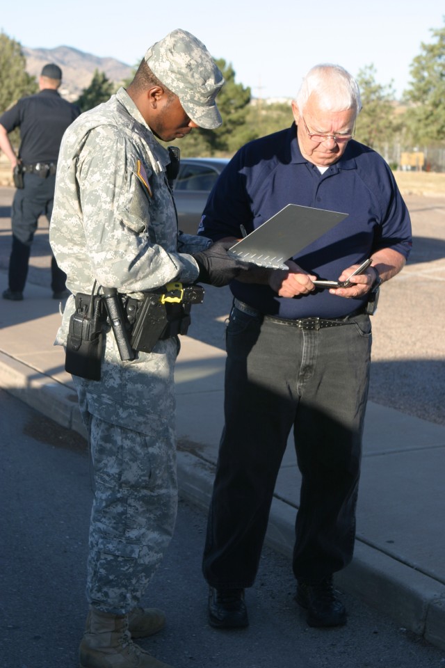 Spc. Daniel Willis, 18th MP Detachment, writes down information from Robert Ordway after Ordway's vehicle was rear ended while entering Fort Huachuca. The accident left no injuries.