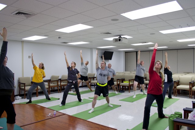 Soldiers and retirees practice reverse warrior pose during a lunch-time yoga class.