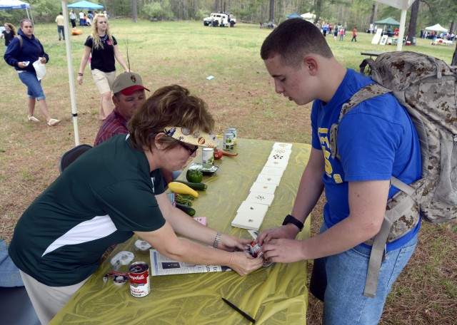 Terry Misch, an Extension Agent with the Virginia Cooperative Extension Service, shows Caroline Middle School student Mark Stephens how to make a biodegradable planter from newspaper. Misch rolled a s