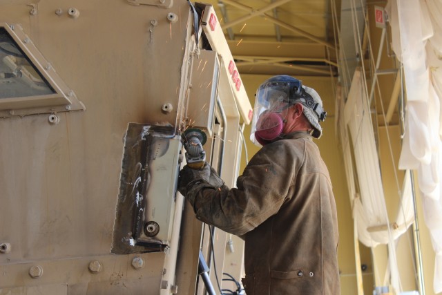 Welder performs finishing touches on welds for the rear wall retention bracket as part of MaxxPro Survivability Upgrade
