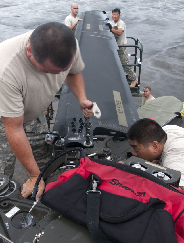 Blackhawk mechanics carefully align the main blades of a UH-60