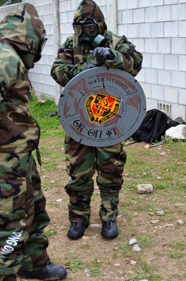 Sgt. Joseph Hudaka communication specialist with Company B, 1st Brigade Support Battalion, 1st Armored Brigade, carries his team's shield into the chemical training facility during the Spartans Shield