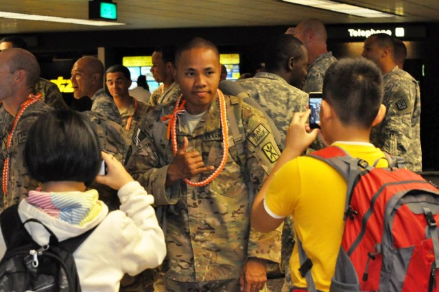 Just back from redeployment, an Alpha Company, 307th Expeditionary Signal Battalion Soldier poses for young tourists