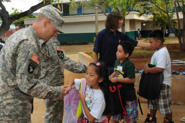 Soldiers and Family members hand school supplies to Fern Elementary School students to fill their new backpacks for the new school year, Sep. 10.