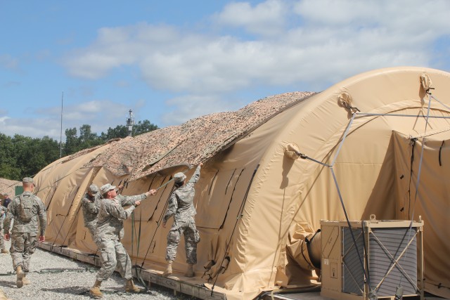 Soldiers install a solar shade on a shelter 
