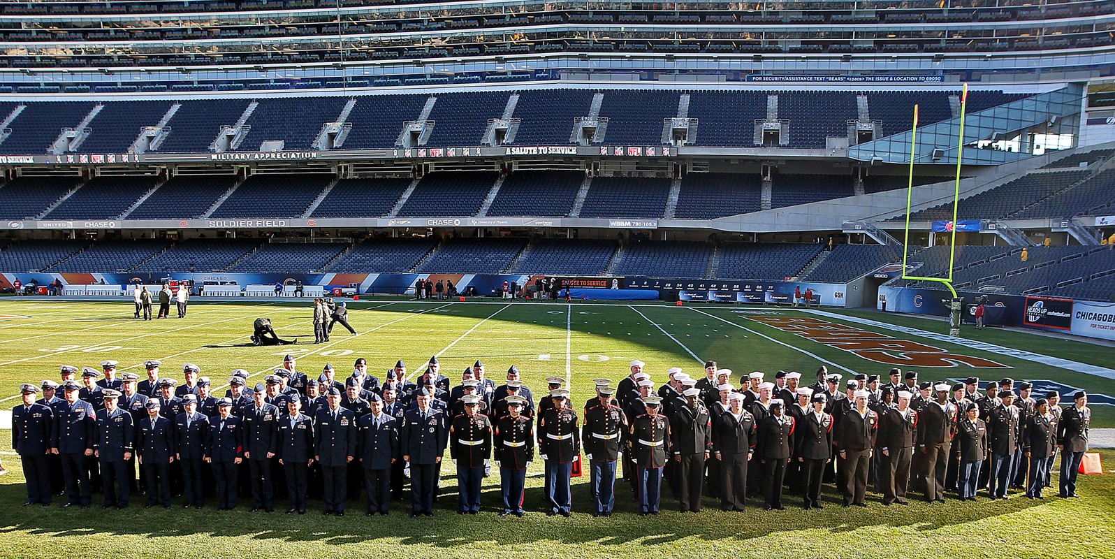 Service members from all five branches of the armed services carry a large  American flag out onto the field at the Salute to Service Chicago Bears  game Nov. 27 at Soldier Field