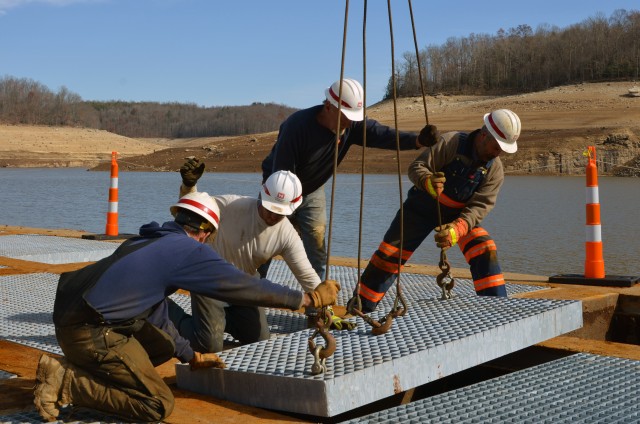 Workers install new deck grating at the Summersville Dam project.