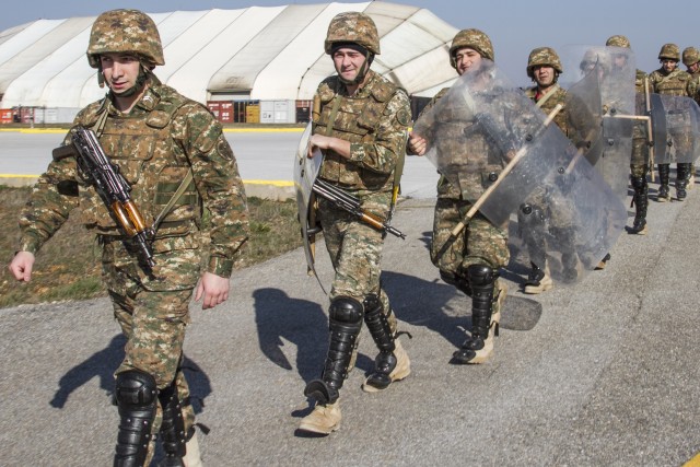 Armenian Soldiers in riot gear approach a UH-60 Black Hawk