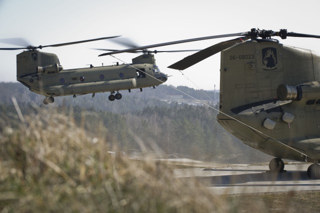 Chinook helicopter hovers in place waiting for execution orders to continue sling load mission