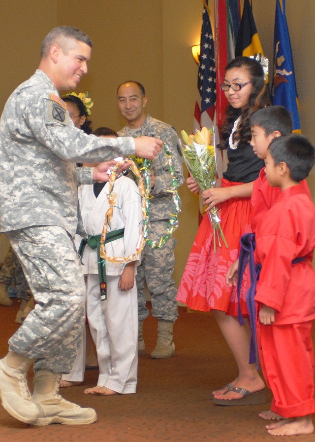 Lt. Col. Fernando Guadalupe, gives leis to Kenji and Connor Kimura at an Asian American Pacific Islander celebration