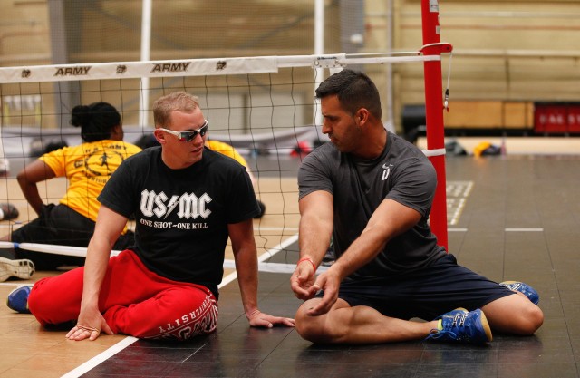 Marine Lance Cpl. Kyle Fellows (left) gets help with sitting volleyball during the 2014 U.S. Army Warrior Trials