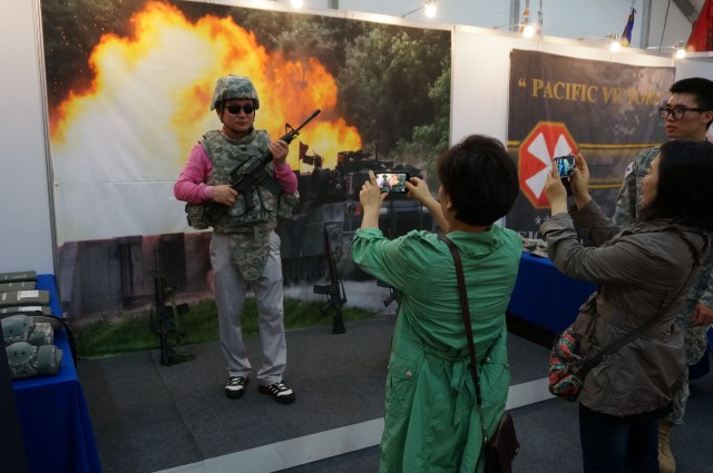 Koreans take photos wearing U.S. Army protective gear and holding mock M4 rifles at the Eighth Army booth at the 2014 RoK Ground Forces Festival, Gyeryong Korea Oct. 2, 2014
