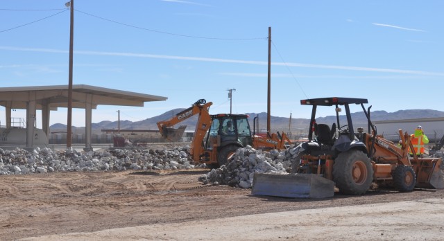Contractors line the berm of a flood channel north of Fort Irwin's military fueling station
