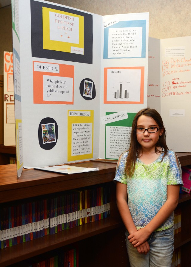 Allison Piper, 11, a fifth grade student in Briarly Mayeda's class, stands alongside her science project,