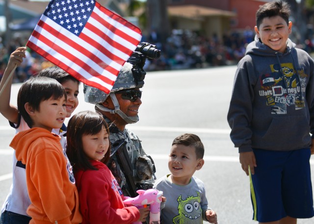 Spc. Matthew Bragg is surrouned by children for a photo