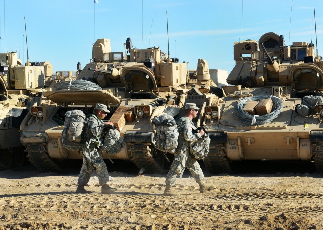 Soldiers of 1st Armored Brigade Combat Team, 1st Cavalry Division carry bags to vehicle