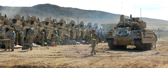 A M2 Bradley Fighting Vehicle moves behind a line of Bradleys
