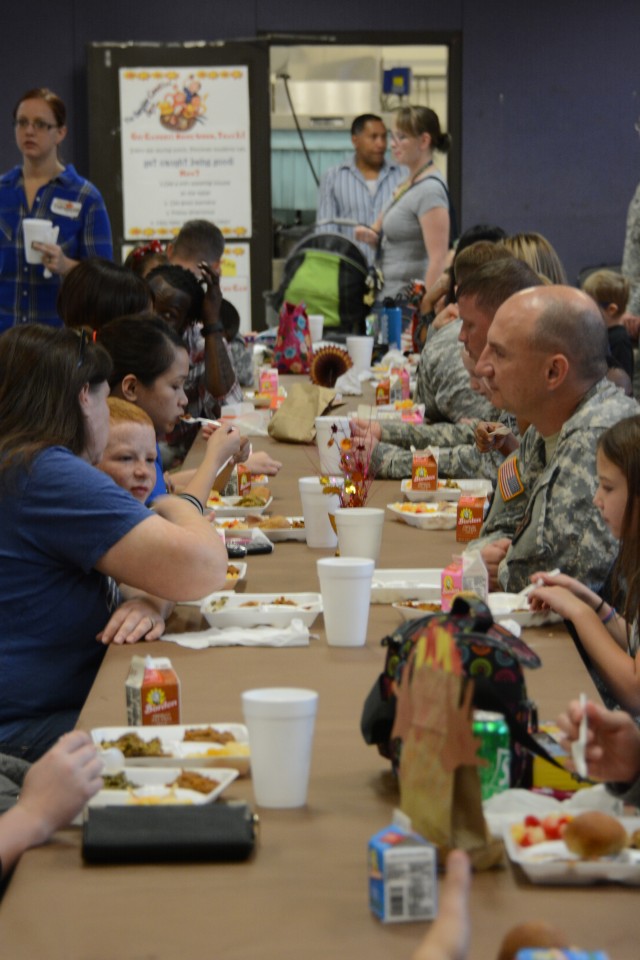 Parents and their children enjoy a Thanksgiving lunch at school