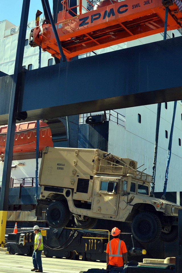 Dock workers at the Port of Anchorage load military vehicles and equipment.