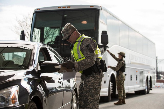 A Joint Base Myer-Henderson Hall military policeman checks driver's identification before granting access to Fort Myer.