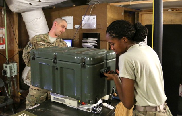 Soldiers weigh a package before mailing