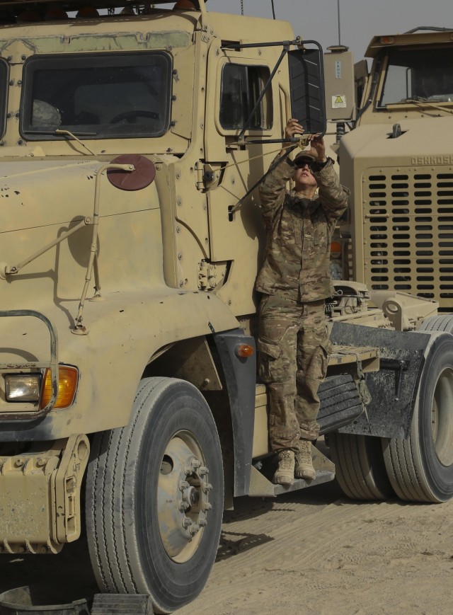 Soldier cleans mirror on her M915A3 truck