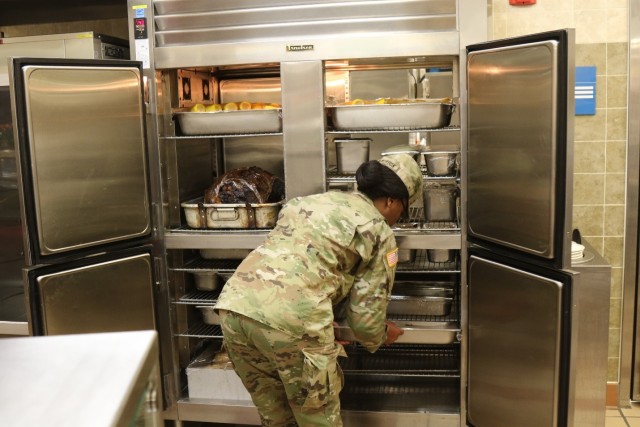 A US Soldier moves the prepared food to the food service line just before the Sustainer Grill Dining Facility opens up for the Thanksgiving Feast.