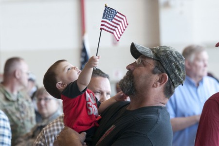 Sgt. Rowdy Blackmon&#39;s son waves an American flag in the arms of his grandfather, father to Blackmon at the Army Aviation Support Facility in Lexington, Ok., June 5, 2016. Members of 1st Airfield Operations Battalion, 245th Aviation Regiment gather with family and friends before deploying to the Middle East to provide air traffic control operations for military and civilian aircraft.