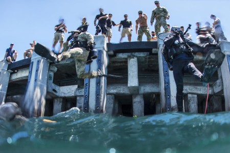 U.S. Army Pfc. Aaron Gaugler and Coast Guard diver 2nd Class Kendall Smith enter the water as part of a pier maintenance training-mission led by Navy Underwater Construction Team 2 during Rim of the Pacific 2016 at Joint Base Pearl Harbor-Hickam, Hawaii, July 12, 2016. The maritime exercise involves about 25,000 participants from 26 nations, 49 ships, six submarines and about 200 aircraft.