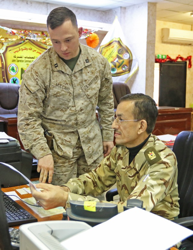 U.S. Marine Cpt. Stephen Mulcahy, CJOC-B Battle Captain, discusses troop movement with Iraqi Maj. Mustafa Muhamed Ameen, Ministry of Defense intelligence representative in the Combined Joint Operation