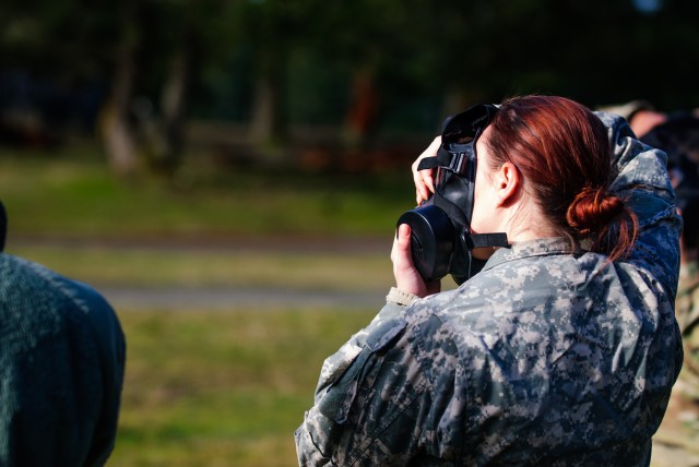 A soldier from Headquarters and Headquarters Company, 301st Maneuver Enhancement Brigade, checks her mask for a proper seal