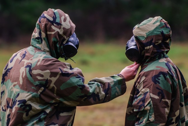 Two soldiers from Headquarters and Headquarters Company, 301st Maneuver Enhancement Brigade, inspect the other's Joint Service Lightweight Integrated Suit Technology (JSLIST)