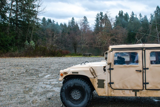 A high mobility multipurpose wheeled vehicle (HMMWV) sits parked in front of Sequalitchew Lake on Joint Base Lewis-McChord, Washington